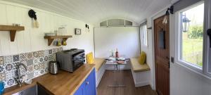 a small kitchen with a refrigerator and a table at Shepherds Hut with Hot Tub in Wells