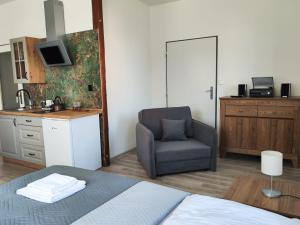 um quarto com uma cama e uma cadeira e uma cozinha em Apartmány Goliáš em Krásná Lípa
