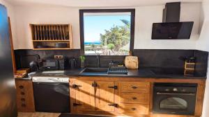 a kitchen with a sink and a stove and a window at Bungalow Allende Famara con piscina privada y AC in Famara