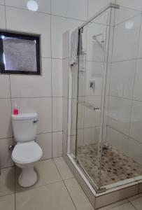 a bathroom with a toilet and a glass shower at Gariep Country Lodge in Prieska