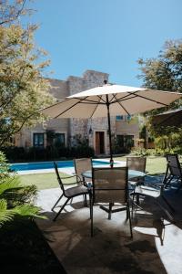 a table and chairs under an umbrella next to a pool at Hacienda Los Arcangeles in San Miguel de Allende