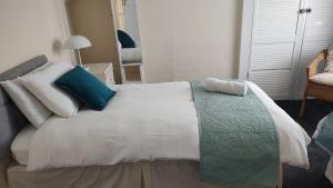 a white bed with blue and white pillows on it at Superior three bedroom house with sea view in Swansea