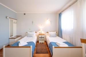 two beds in a small room with a window at Hotel Rozmaryn i Lawenda in Minikowo