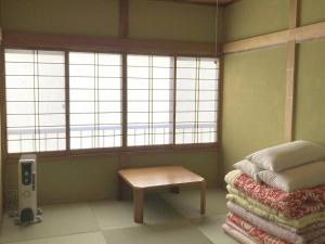 Schlafzimmer mit einem Bett, einem Tisch und Fenstern in der Unterkunft Lake Shoji Hutte - Vacation STAY 92452v in Narusawa