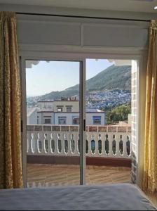 a bedroom with a large glass door to a balcony at Appartement aboubakr ahayek in Chefchaouen
