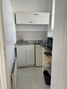 uma pequena cozinha com um lavatório e armários brancos em Tiers lieu de l'Ermitage em Versalhes