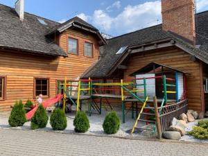 plac zabaw przed drewnianym domem w obiekcie Gościniec Konopielka w mieście Zblewo