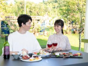 un hombre y una mujer sentados en una mesa con comida y vino en BAMBOO RESORT MIHAMA TSUNAGI - Vacation STAY 43081v, en Noma