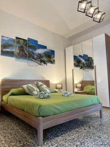 um quarto com uma cama com lençóis e almofadas verdes em Valverde75 Guesthouse em Alghero