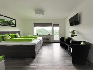 a bedroom with two beds and a tv and chairs at Gästehotel Lucendi Premium Lounge in Hohenleimbach