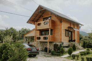 a log cabin with a car parked in front of it at Айворі Хаус in Mykulychyn