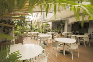 a restaurant with white tables and chairs and plants at Torres de Alba Hotel & Suites in Panama City