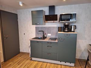 eine Küche mit einer Spüle und einer Mikrowelle in der Unterkunft Pension Eichsfeld Zimmer 4 Standard in Breitenworbis