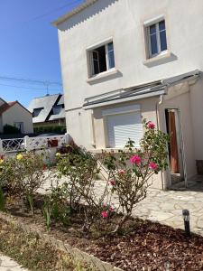 una casa blanca con flores rosas en un patio en Ker LN, en Saint-Nazaire