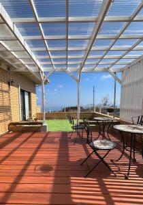 eine Terrasse mit Tischen und Stühlen unter einer Pergola in der Unterkunft Masaya Villa - Vacation STAY 23218v in Ito