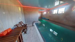 a swimming pool in a room with two benches at Apartamenty i pokoje z basenem AVENA Jastrzębia Góra in Jastrzębia Góra
