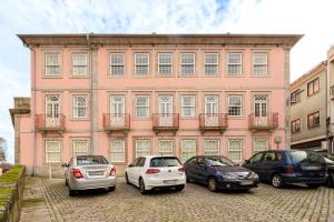 a pink building with cars parked in front of it at Fontainhas Hidden Gem in Porto