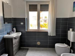 uma casa de banho com um lavatório, um WC e uma janela. em Camere Giulia em Bérgamo