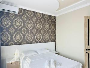 sypialnia z białym łóżkiem i tapetą damaskową w obiekcie House in Tsikhisdziri w Kobuleti