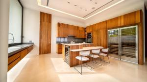 a kitchen with wooden cabinets and a island with bar stools at Sunny Vacation Villa no 1 in Bonao