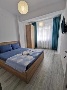 een slaapkamer met een blauw bed en een televisie bij Promenada 1-4 in Mamaia Nord – Năvodari