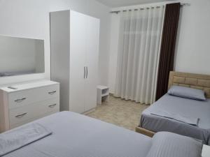 a bedroom with two beds and a dresser with a tv at Apartamente Kune Shengjin in Lezhë