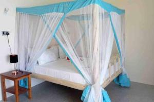 una camera con letto a baldacchino con tende e tavolo di Kome apartment two a Jambiani