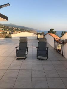 three chairs sitting on a patio with a view of the ocean at La terrazza di Brancaccio’s house summer in Paola