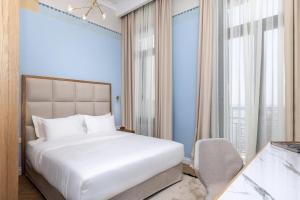 a bedroom with a large white bed and a chair at EPICURE SUITES in Kavala