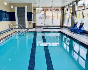 uma grande piscina com cadeiras azuis num edifício em Four Points by Sheraton Kelowna Airport em Kelowna