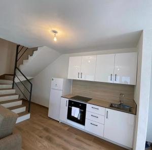 a kitchen with white cabinets and a staircase at Villat Twin’s in Peje