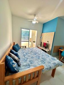 1 dormitorio con 1 cama grande con sábanas y almohadas azules en Apto. novo, todo equipado, 330m da praia en Ubatuba