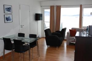 uma sala de estar com uma mesa de vidro e cadeiras pretas em Smaken av Ryfylke, restaurant og overnatting em Hjelmeland