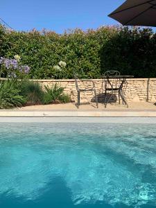 un banco y una sombrilla junto a la piscina en Le Cabanon de Livia avec piscine privée en Cucuron