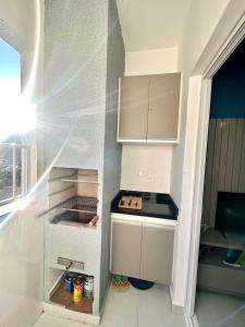 cocina pequeña con armarios blancos y fogones en Apto. novo, todo equipado, 330m da praia en Ubatuba