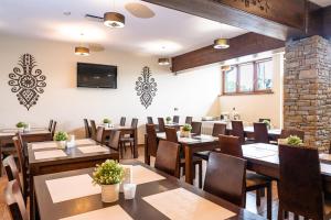 un restaurante con mesas y sillas de madera y TV de pantalla plana en Willa Szafran, en Dzianisz