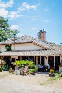 a house with chairs and a table in front of it at La Ferme du Miouat in Saint-Julien-en-Born