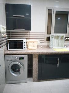 a kitchen with a washing machine and a microwave at LA PERLE DE L'OCEAN 1 in Akhfennirr