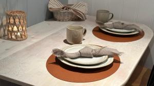 a table set with plates and mugs and a napkin at “ Mandala” place for 2 in Sauda