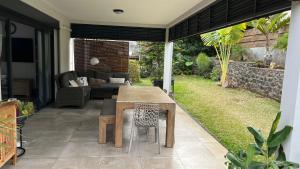 un patio con una mesa de madera y un sofá en Villa HIMANI, en Saint-Gilles-les-Bains