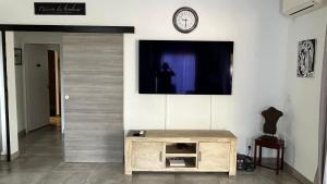 a room with a tv on a wall with a wooden table at Villa HIMANI in Saint-Gilles les Bains