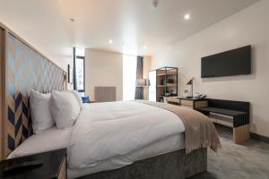 a bedroom with a large bed and a television at Sandman Signature Glasgow Hotel in Glasgow