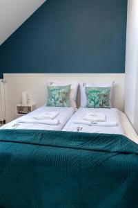 two beds in a bedroom with a blue wall at Nowe Apartamenty z antresolą z 2 sypialniami - REWAL in Rewal