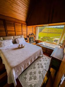 a bedroom with a bed and a large window at Chalés Grecco in Venda Nova do Imigrante