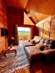 a living room with a leather couch and a large window at Chalés Grecco in Venda Nova do Imigrante