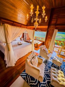 a bedroom with a bed and chairs and a chandelier at Chalés Grecco in Venda Nova do Imigrante