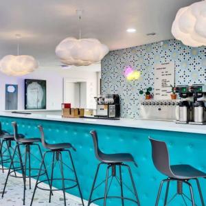 a bar with black stools and a blue counter at Hotel McCoy - Art, Libations, Pool Society in College Station
