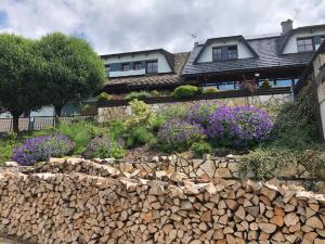 eine steinerne Mauer vor einem Haus mit lila Blumen in der Unterkunft Horský hotel Hájenka in Makov