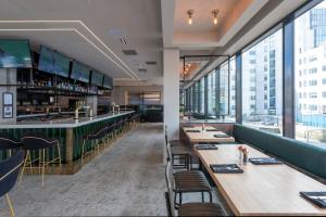 a restaurant with wooden tables and chairs and large windows at Sandman Signature Glasgow Hotel in Glasgow