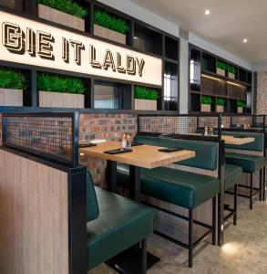 a restaurant with wooden tables and green chairs at Sandman Signature Glasgow Hotel in Glasgow